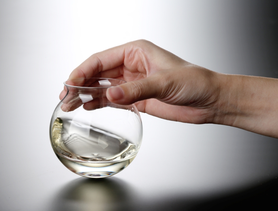 日本酒が注がれたグラスを手にとっている写真
